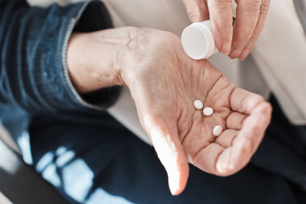 istock Senior woman's hands tipping pills from container 1159368118