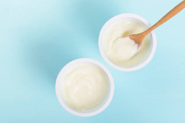 istock Plastic cup of yoghurt with wooden spoon 1159368151