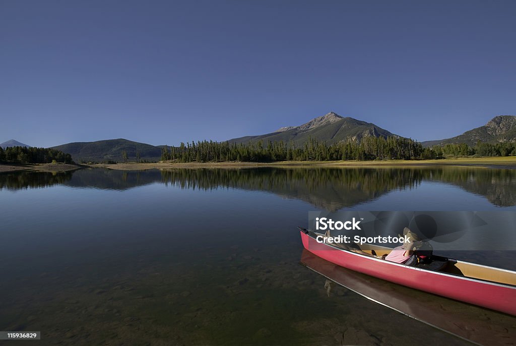 Belle femme de détente dans un canoë au lac de montagne - Photo de Canoter libre de droits