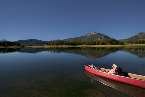Woman Relaxing in Canoe on Lake with Mountain View