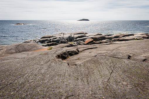 Sea landscape of a rocky coastline and a small town on the South of Sweden. Southern coastline of Sweden with view at rocky islands. White yacht in the sea.