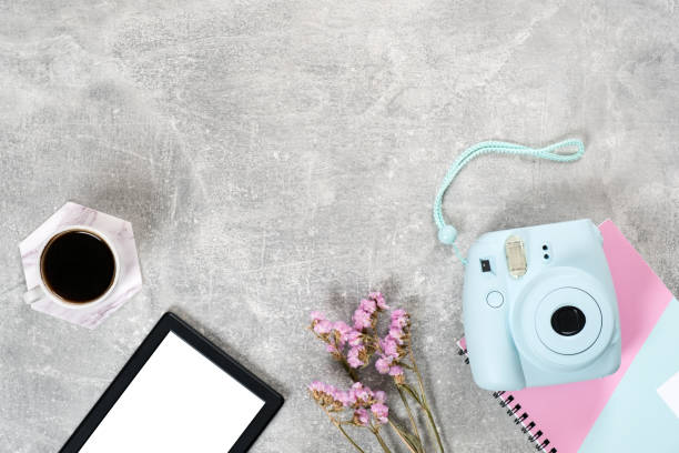 istock Flat lay feminine accessories: instant film camera coffee cup, dry flowers and e book reader on concrete surface. Top view beauty blogger workspace, freelancer home office desk. Fashion blog hero. 1159371523