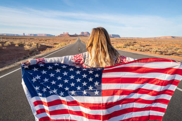 istock Girl on road holding American flag 1159372475