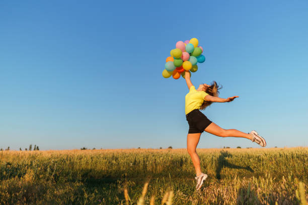 istock Happy woman jumping with multicolored balloons 1159372556
