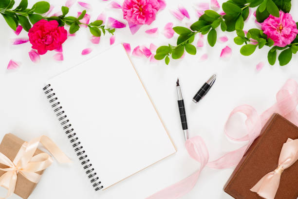 istock Stylish composition with pink rose flowers, blank paper notepad, ribbon, pen gift box on white background. Woman home office desk, flat lay, top view. 1159373842