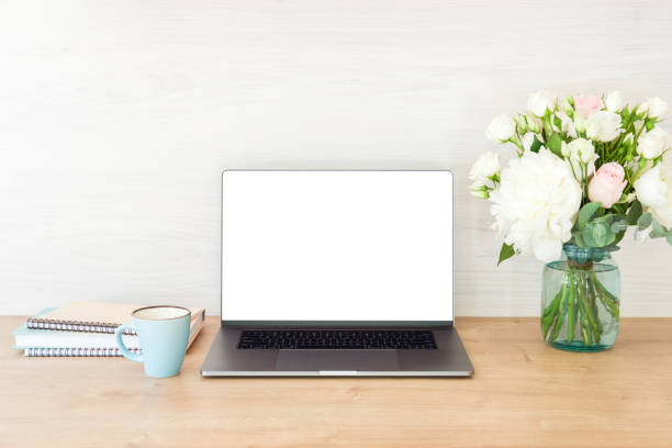 istock Office desk table with laptop computer with blank screen mockup, supplies, cup of coffee, flowers bouquet on wooden surface. Business woman workspace concept 1159375476