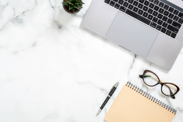 istock Marble office desk table with laptop computer, paper notepad, glasses, succulent plant, stationery. Minimal flat lay style composition, top view, overhead. Business woman workspace concept. 1159376144