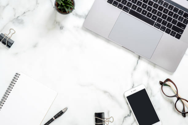 istock Marble office desk table with laptop computer, paper notepad, phone, glasses, succulent plant, stationery. Minimal flat lay style composition, top view, overhead. Business woman workspace concept. 1159376150