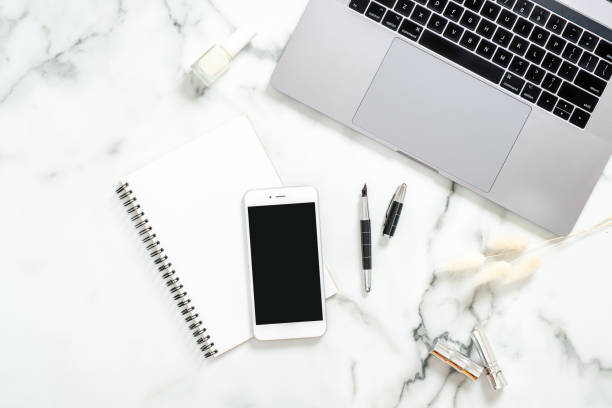 istock Flat lay home office desk. Female workspace with laptop computer, dry flowers, paper notepad, smartphone on marble background. Top view feminine background. Business woman workplace concept. 1159376156