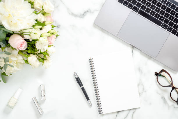 istock Flat lay home office desk. Women workspace with laptop computer, flowers bouquet, diary, glasses, accessories on white marble surface. Top view feminine background. Girl's workplace concept. 1159376164