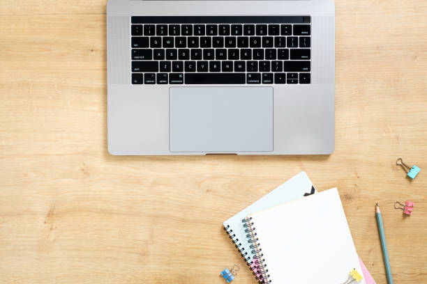 istock Wood office desk table with modern laptop computer, blank paper notepad, pen, stationery, clips. Minimal flat lay style composition, top view. Business concept. 1159376165