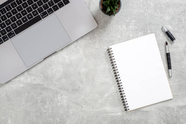 istock Office desk table with laptop computer, succulent plant, blank paper notepad on concrete stone background. Flat lay, top view workspace 1159376207