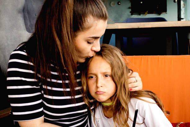 istock Supportive sister. Loving supportive younger sister kissing her while she is sad 1159376208