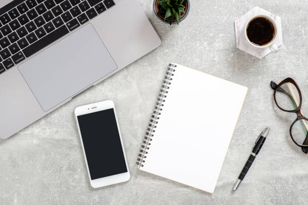 Flat lay office desk. Female workspace laptop computer, blank copy space mockup screen smartphone, coffee cup, diary, glasses. succulent plant on concrete stone background. Top view feminine workspace