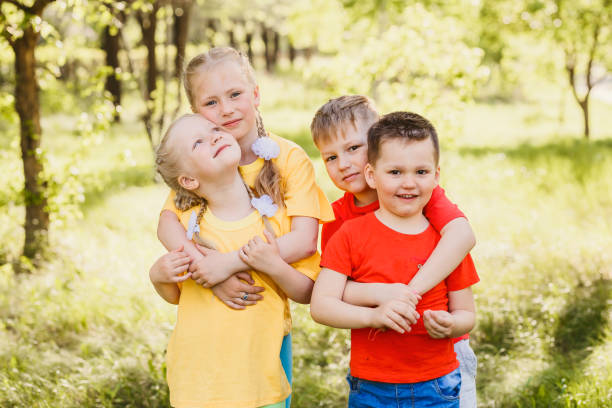 istock four fun happy kids hugging outdoors 1159377783
