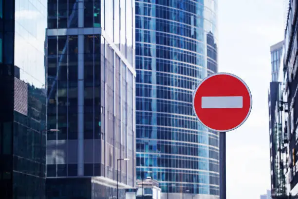 Photo of Red road stop sign or brick on city skyscrapers business center blurred background close up, entrance prohibition, restriction or no way symbol, no entry allowed or forbidden traffic sign, copy space