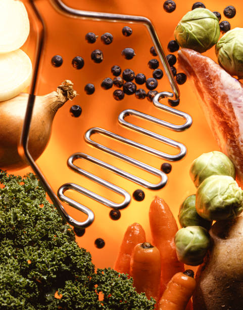 Studioshot of a masher and ingredients for a stew, like carrot, potato, onion, sprouts bacon,  pepper, kale, bacon