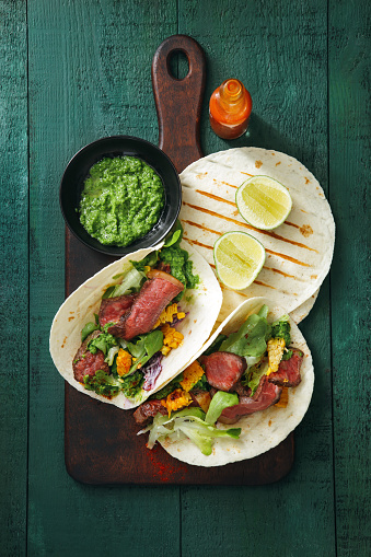 Chili lime steak tacos on green background