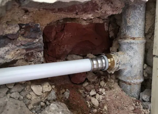 old waterpipes in the wall with a new part made of plastic