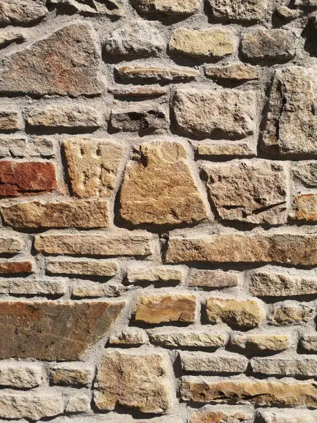 Old cemetery wall, made of quarrystone, in strong sunlight with high contrast