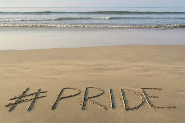 Stock photo of hashtag tag writing on sunny beach with Pride words written in sand by sea, Palolem Beach, Goa, India, concept social media photo of handwriting in golden sand with modern hashtag prefiix imagen de hashtag tag etiqueta escritura en playa soleada con palabras orgullo escritoen en arena por mar, palolem beach, goa, india, concepto de la foto de las redes sociales de escritura a mano en arena dorada con el hashtag moderno prefiix