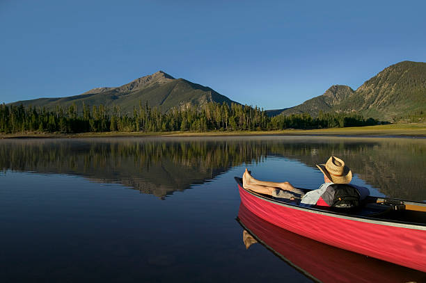 homme relaxant en canoë avec vue sur la montagne - southern rocky mountains photos et images de collection