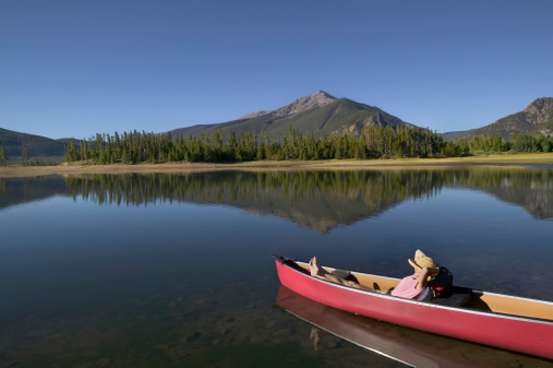 Woman Relaxing in Canoe on Lake with Mountain View
