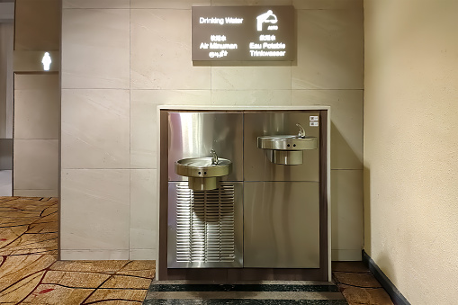 Water drinking fountain in a public place.  Modern device of stainless steel for drinking in airport.