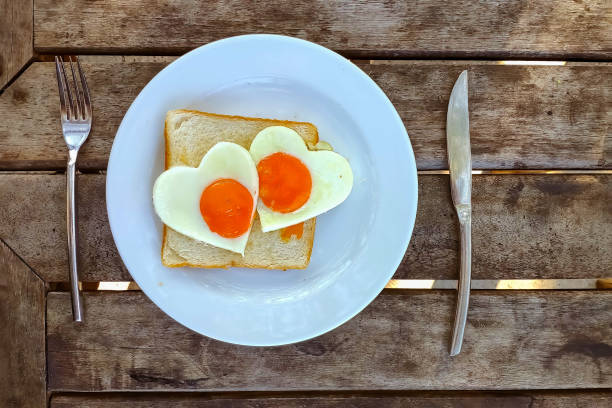 istock Toast with scrambled eggs in the shape of a heart on a white plate. 1159384636