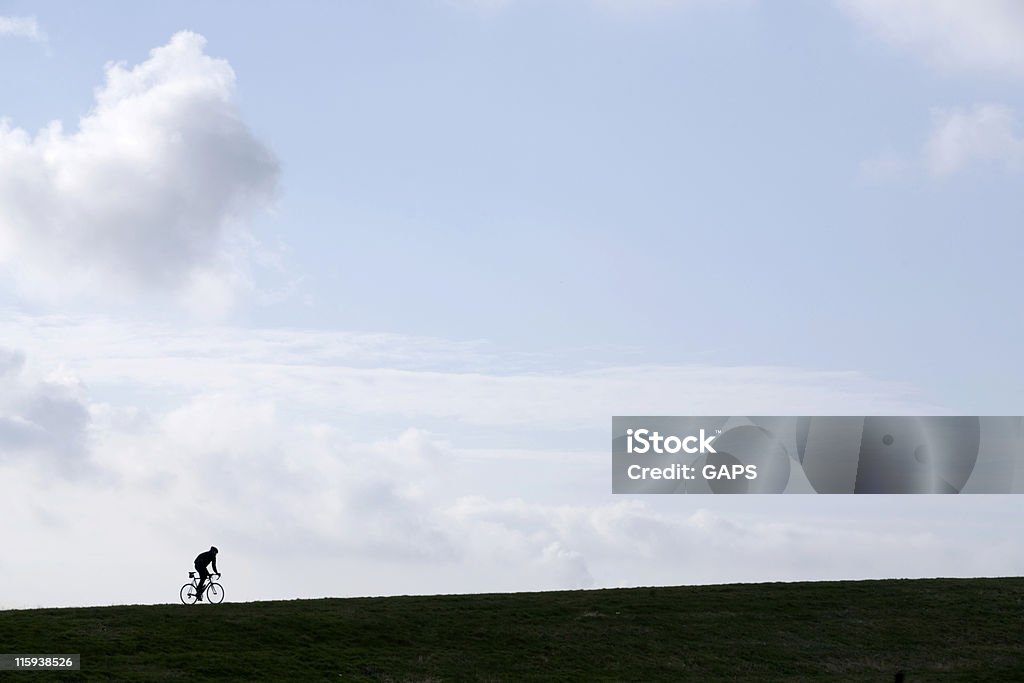 Arrampicata su una collina silhouetted ciclista - Foto stock royalty-free di Allenamento