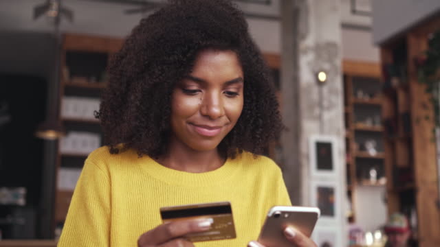 Young woman shopping online on mobile phone with credit card