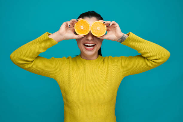 istock Playful girl holding orange slices, doing binoculars. 1159387256