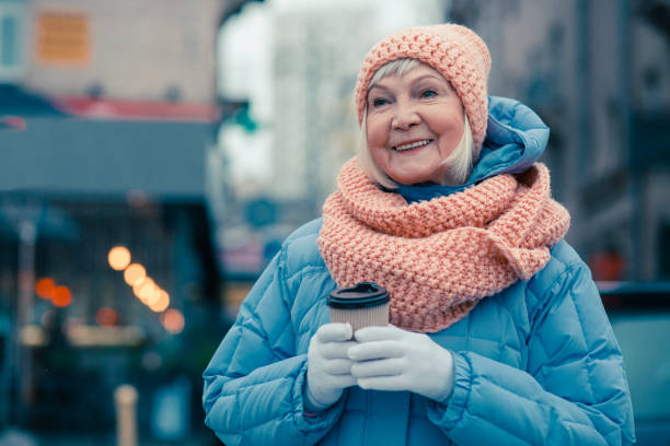 istock Positive aged woman smiling while standing with cup of coffee 1159387331