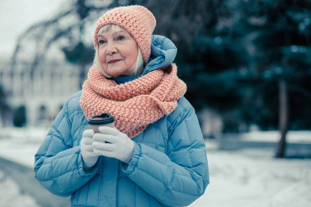 istock Calm elderly lady in winter coat standing outdoors with coffee 1159387456