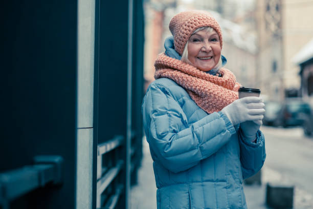 istock Delighted aged lady with coffee being outdoors and smiling 1159387468