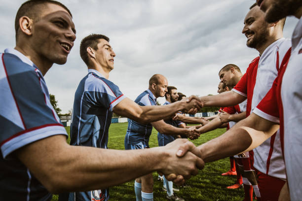 istock Happy sportsmen shaking hands before a match on a playing field. 1159388660