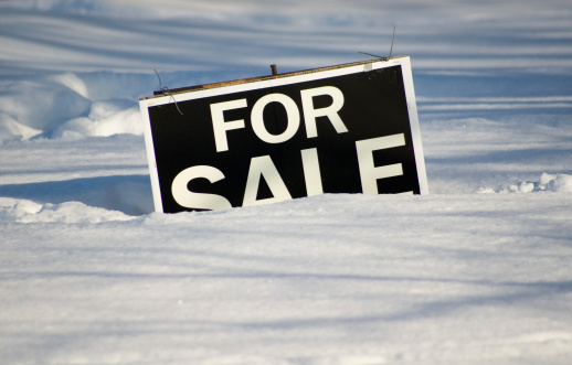 Real estate for sale sign partially buried under a very heavy snowfall