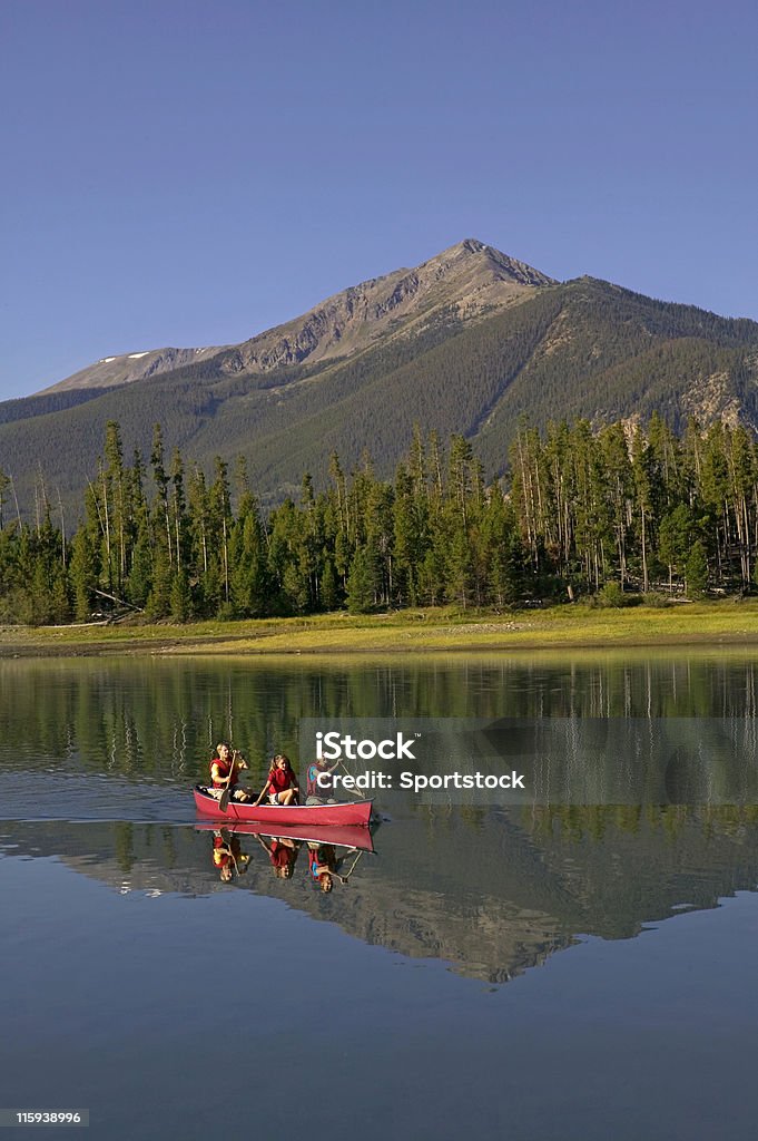 Famiglia in canoa sul lago di montagna con riflessione - Foto stock royalty-free di Acqua