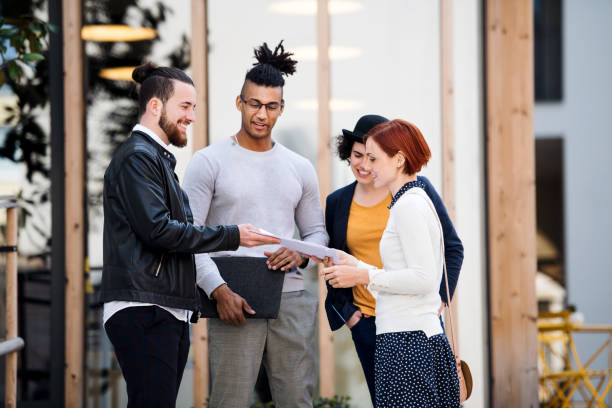 istock Group of young businesspeople standing outdoors in courtyard, talking. 1159390043
