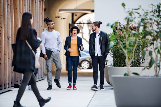 istock Group of young businesspeople walking outdoors in courtyard, talking. 1159390048