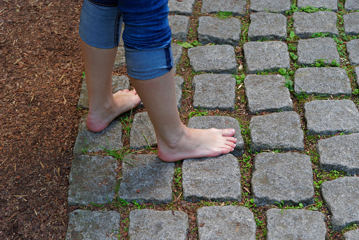 Female bare feet on paved path in the country. Egestorf, Germany