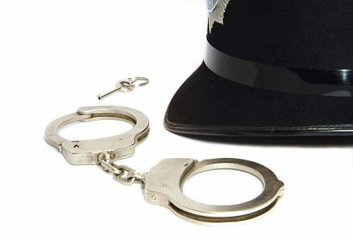 A British Police helmet together with a pair of issue handcuffs and the key all isolated on white. No sharpening in camera or pp.