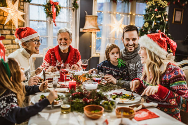 glückliche großfamilie mit neujahrsmittagessen am esstisch. - weihnachten familie stock-fotos und bilder