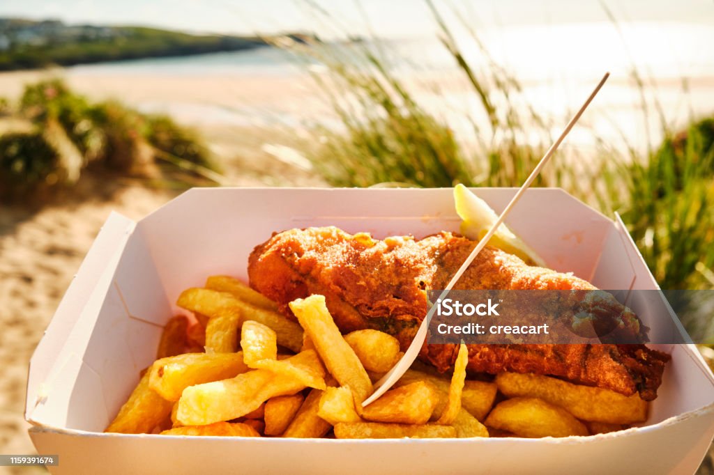 box of Fish and Chips at Fistral Beach, Newquay, Cornwall on a sunny June evening. Fish and Chips Stock Photo