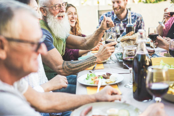 Happy family eating and drinking wine at barbecue dinner on patio outdoor - Mature and young people having fun at bbq sunday meal - Food and summer lifestyle concept - Focus on hipster man arm hand Happy family eating and drinking wine at barbecue dinner on patio outdoor - Mature and young people having fun at bbq sunday meal - Food and summer lifestyle concept - Focus on hipster man arm hand english cuisine stock pictures, royalty-free photos & images