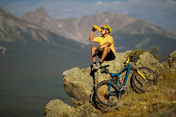 Biker in Mountains Drinking From Water Bottle stock photo