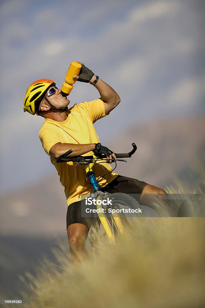 Mann auf Fahrrad trinkt aus Flasche Wasser - Lizenzfrei Abgeschiedenheit Stock-Foto