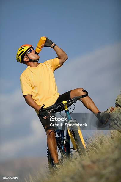 Foto de Homem Em Bicicleta De Beber Da Garrafa De Água e mais fotos de stock de Adulto - Adulto, Amarelo, Artigo de vestuário para cabeça