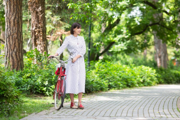 istock Young woman with bicycle in park 1159393173