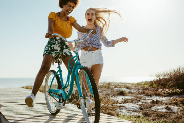 ragazze allegre che si divertono con un ciclo - bicycle ride foto e immagini stock